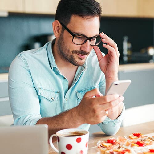 Man checking his phone in the kitchen.