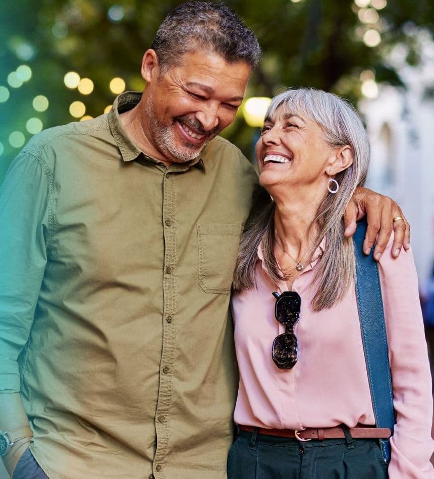 A smiling older couple out on the street, next to the app and glucose sensor they use every day.